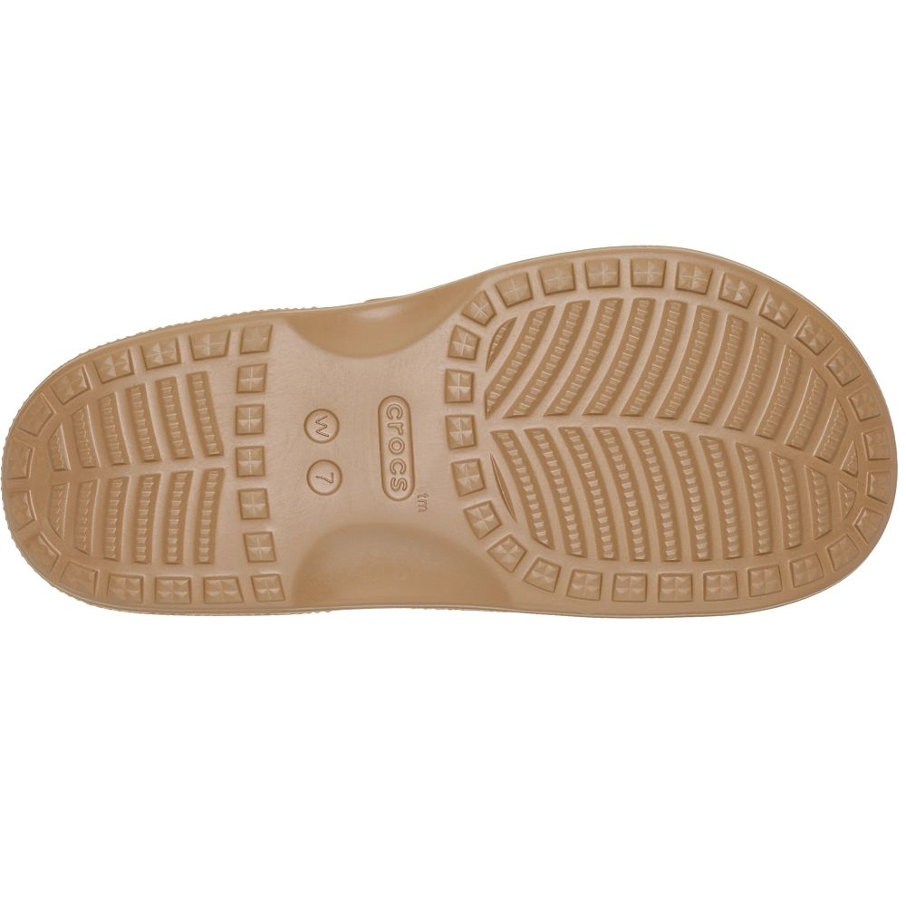 A top-down view of a tan Crocs sole with detailed tread patterns and the Crocs logo embossed in the center, set against a plain white background.