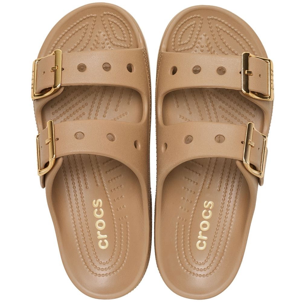 A pair of tan Crocs double-strap slide sandals with gold-tone buckle closures, shown from a top-down view on a white background.