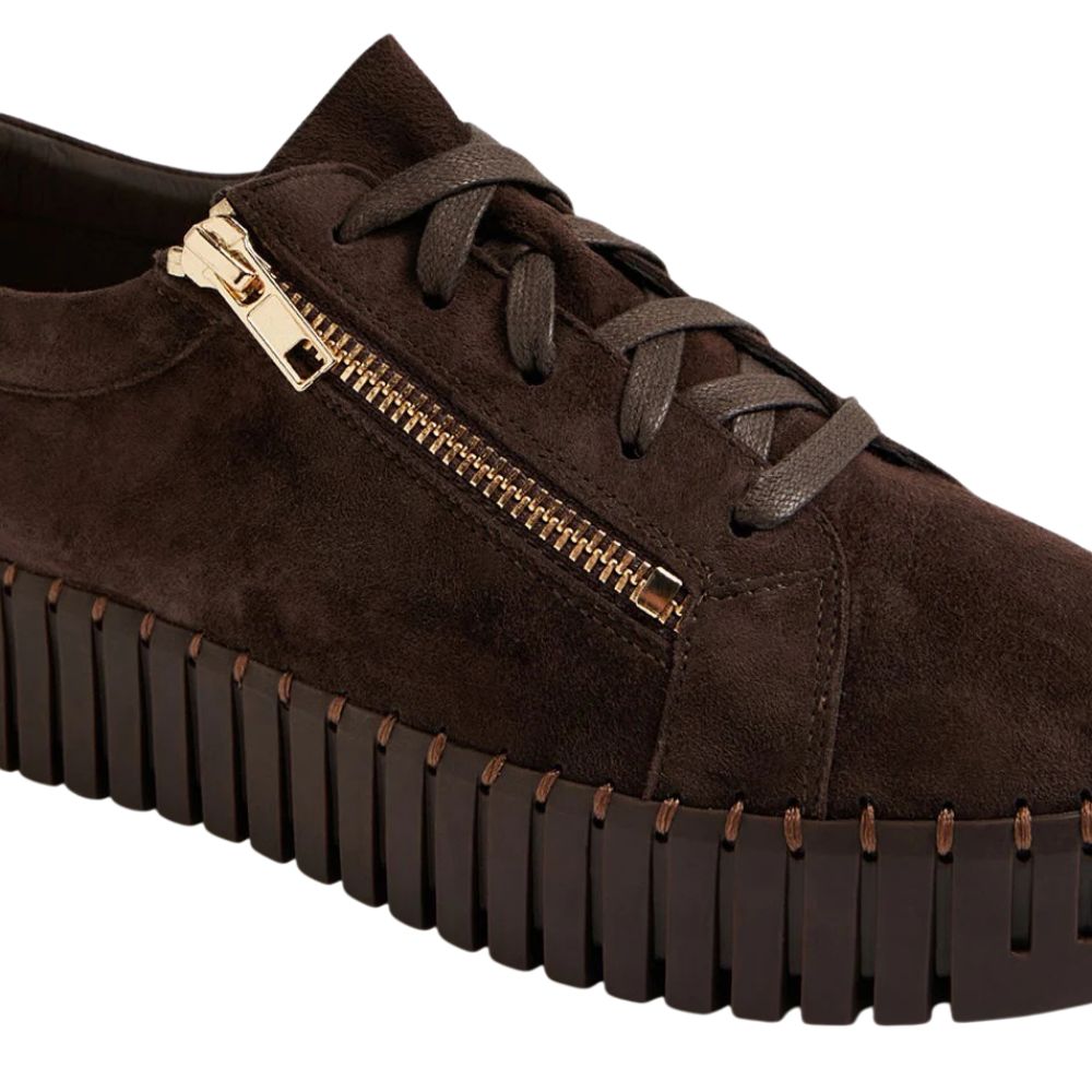 Brown suede sneaker with gold zipper and unique sole design on a white background