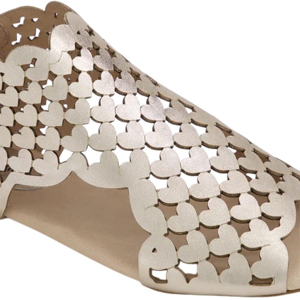 A close-up of a metallic champagne gold peep-toe flat sandal featuring a laser-cut heart pattern across the upper.