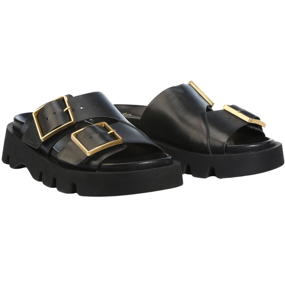 A pair of black leather double-strap slide sandals with chunky lug soles and prominent gold-tone square buckle details, shown against a plain white background.