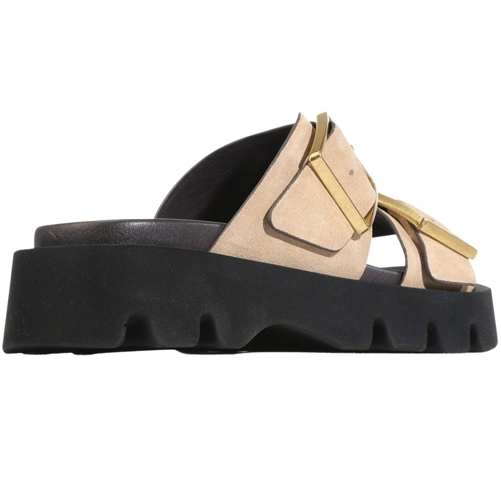 A single platform slide sandal with a chunky black sole, beige suede straps, and gold-tone buckle details, shown from a side profile view on a white background.