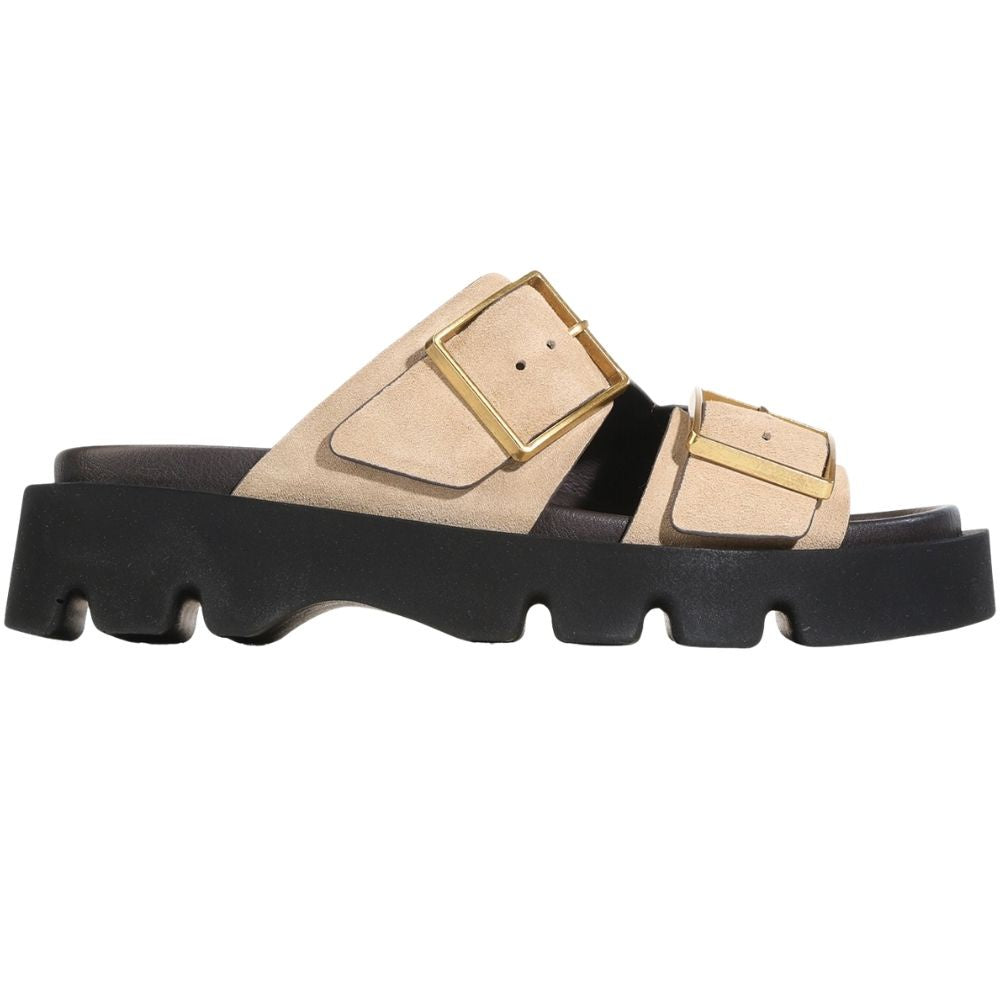 A beige double-strap slide suede leather sandal with chunky gold-tone buckles and a thick black lug sole, shown in a side profile on a white background.