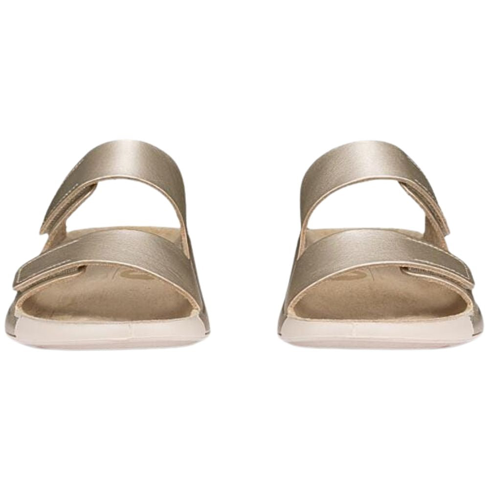 Front view of a pair of pale gold sandals with two adjustable straps on a white background