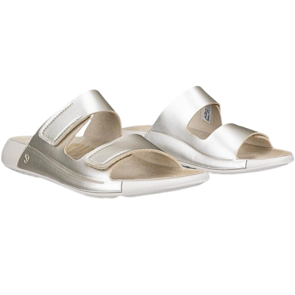 A pair of metallic pale gold slide sandals with two adjustable straps, shown on a plain white background.