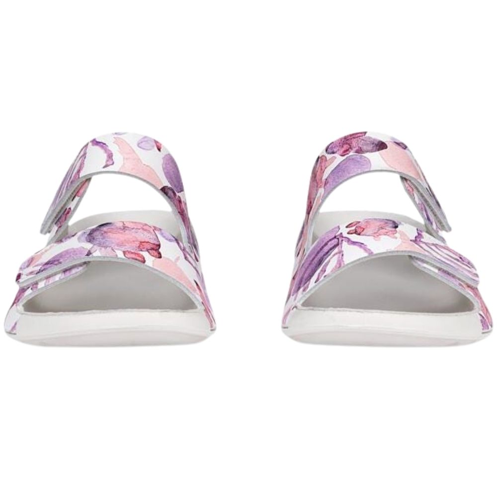 A pair of women's slide sandals with a white sole and a strap featuring a pink and purple watercolor floral pattern on a white background.