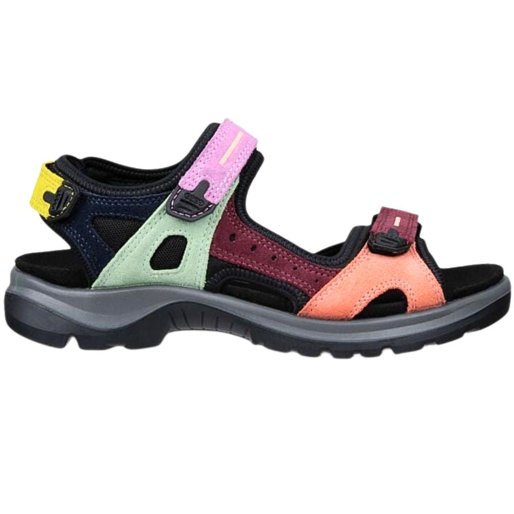 A multicolor offroad sandal with a black sole and straps, featuring panels of light green, burgundy, coral orange, and pink, along with a yellow heel tab, shown against a plain white background.