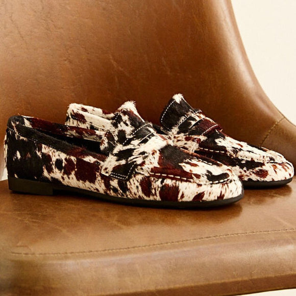 Pair of animal print patterned loafers on a brown surface