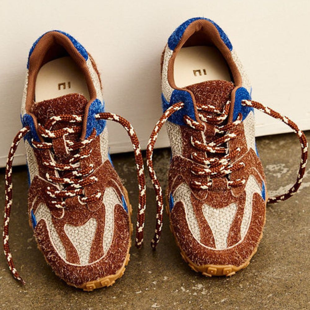 Pair of brown and blue sneakers on a concrete floor.