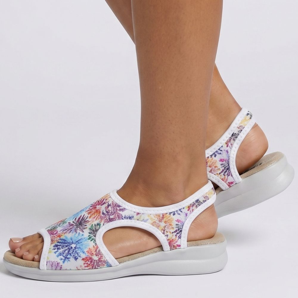 Person wearing multicolored floral sandals on a white background