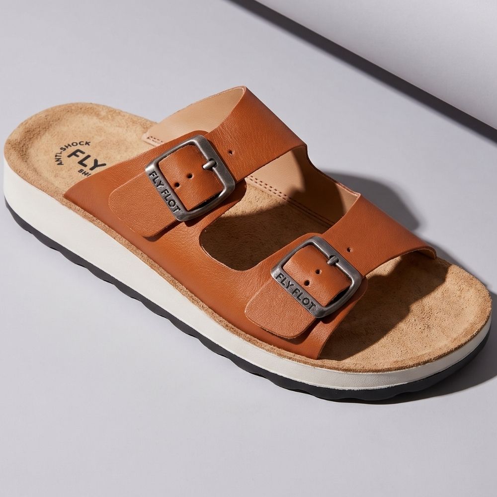 Italian tan leather slide sandal by 'Fly Flot' with two adjustable buckle straps, against a white studio background.
