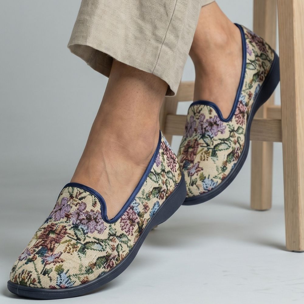 Floral-patterned slippers worn by a person sitting on a chair.