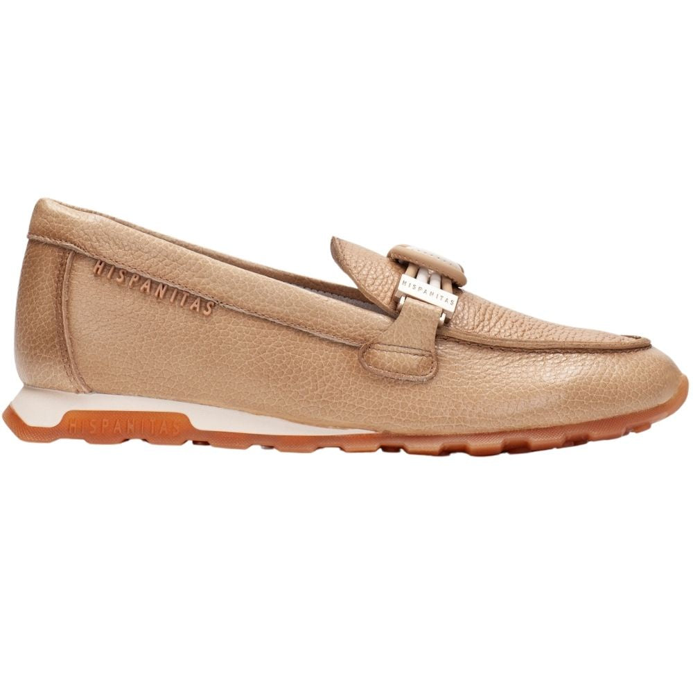 A tan pebbled leather slip-on loafer from Hispanitas, featuring a decorative strap with a gold-tone buckle across the vamp and a white midsole.