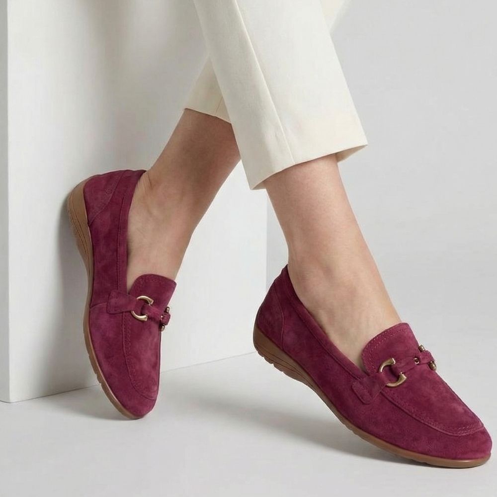 Merlot loafers with a gold horse-bit detail, worn with white pants on a light background