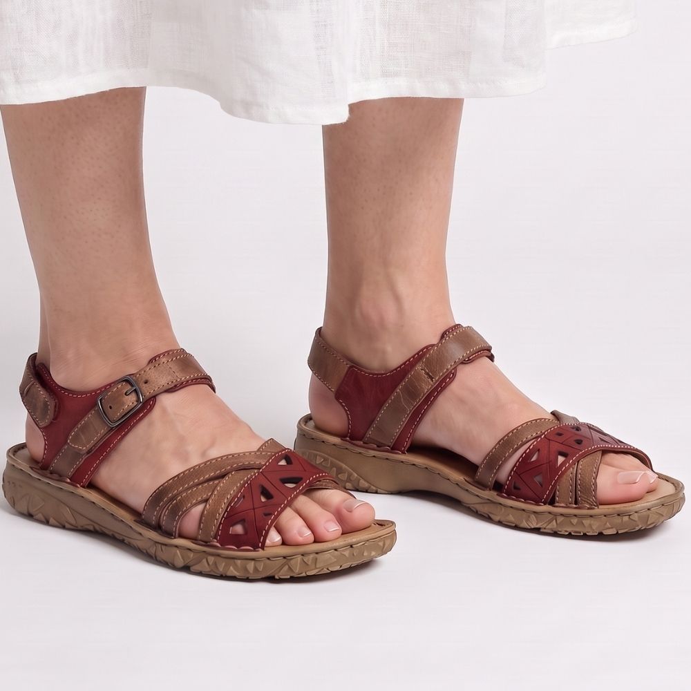 Brown and burgundy-red leather sandal with cut-out designs on a brown textured outsole, against a white background.