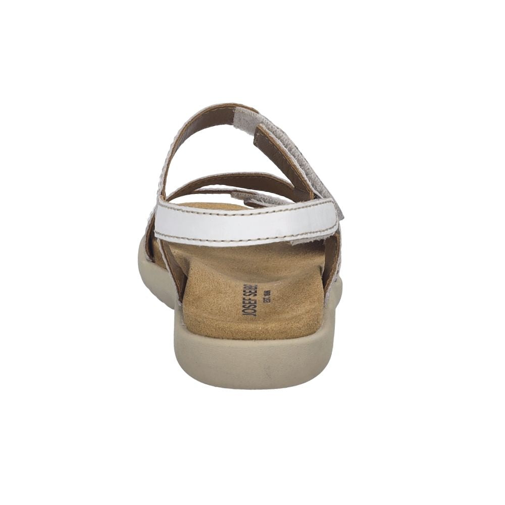 A single women's flat sandal shown from a rear three-quarter view, featuring a white upper strap, a tan suede-like footbed, and a beige sole, on a plain white background.
