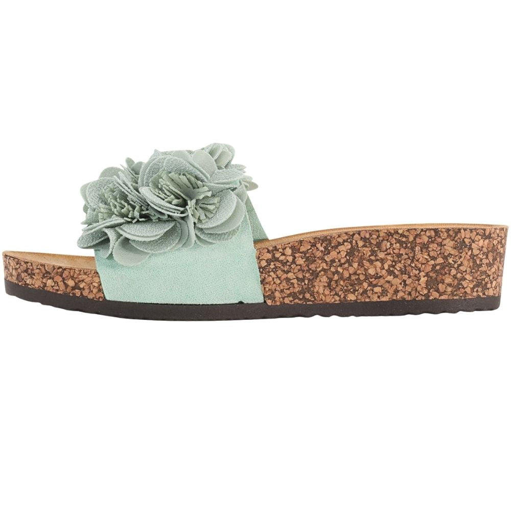 A mint slide sandal featuring a large fabric flower embellishment on the strap, a tan cork-look wedge heel, and a black outsole, shown against a plain white background.