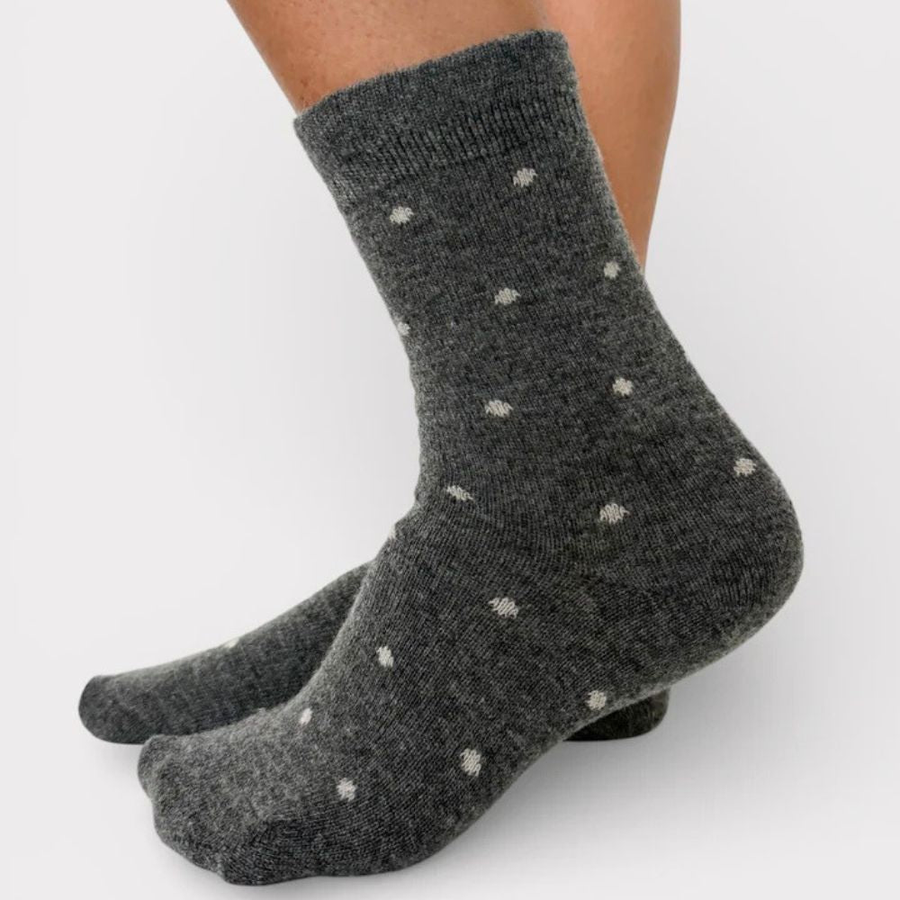 Person wearing grey frill top crew socks with white polka dots on a white background
