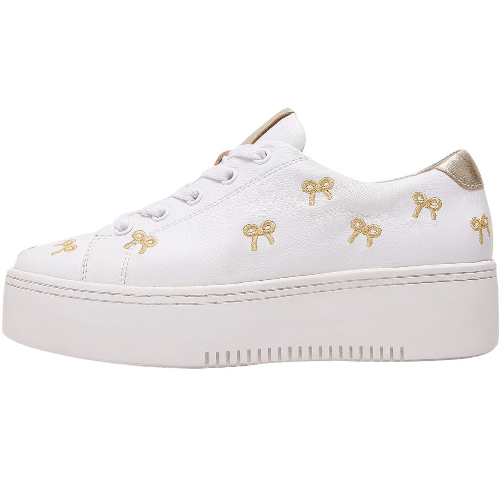 White sneaker with gold bow designs on a white background