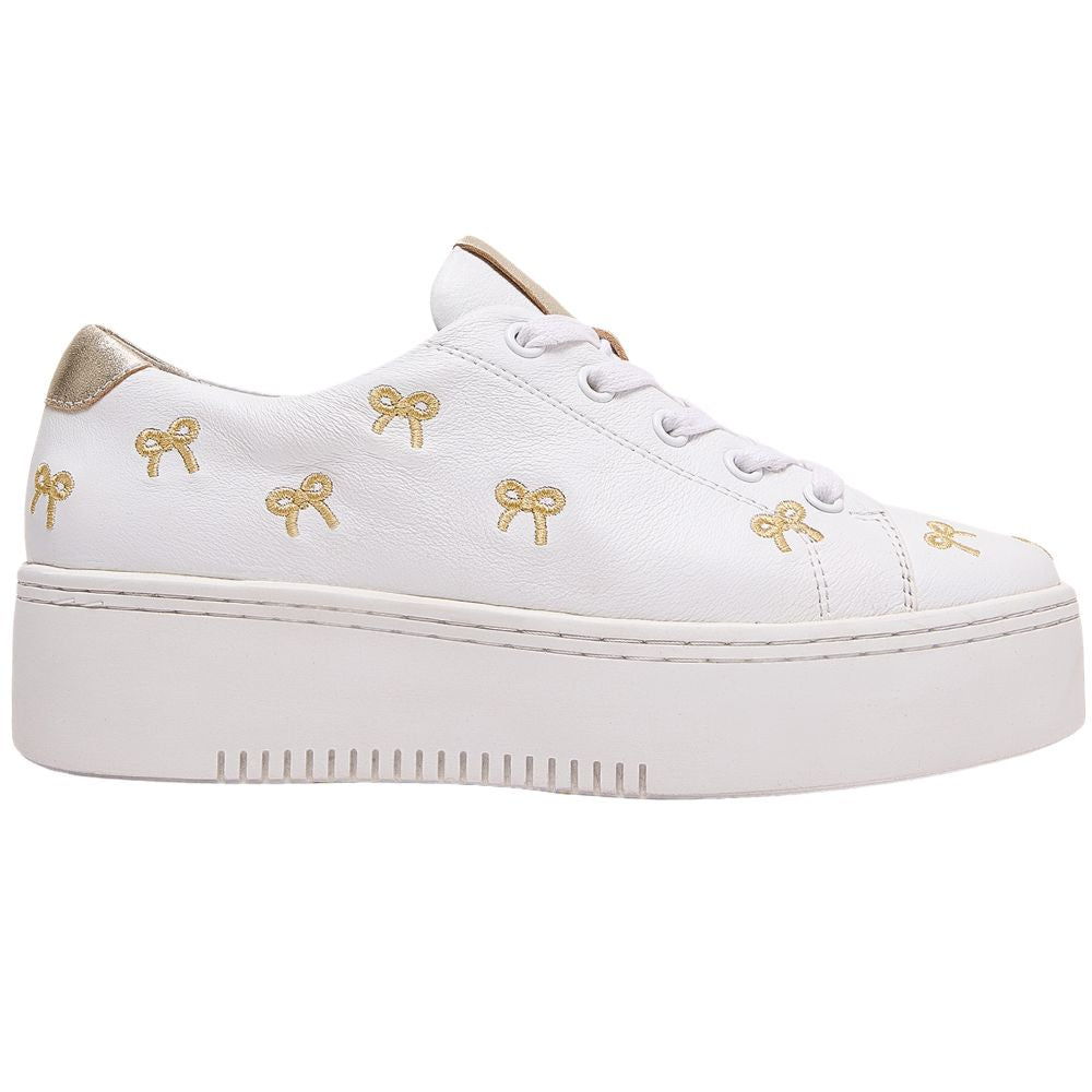 White sneaker with gold bow designs on a white background