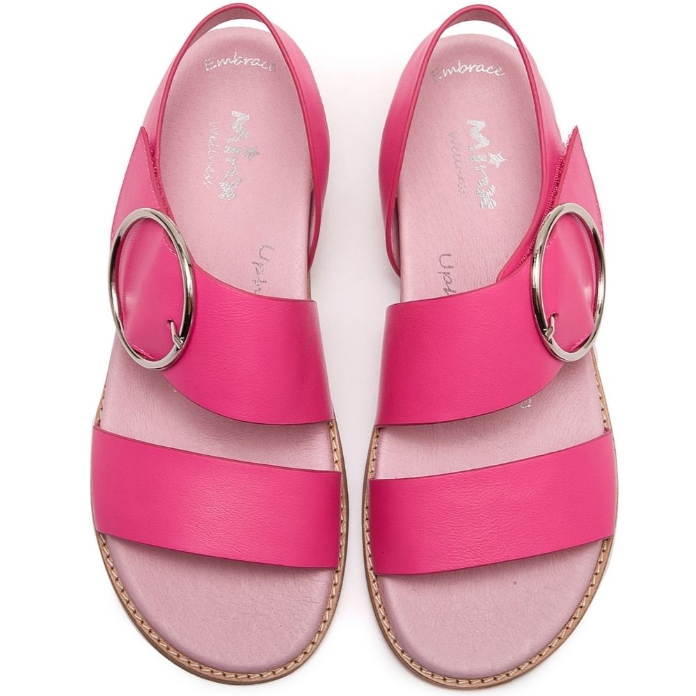 A pair of women's flat sandals in vibrant pink, featuring wide double straps with large silver-tone circular metal rings, shown from a top-down view on a white background.