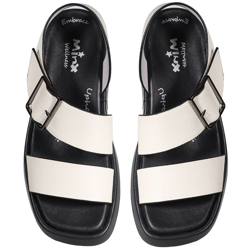 A pair of black and off-white slide sandals with wide horizontal straps and adjustable side buckles, shown from a top-down view on a white background.