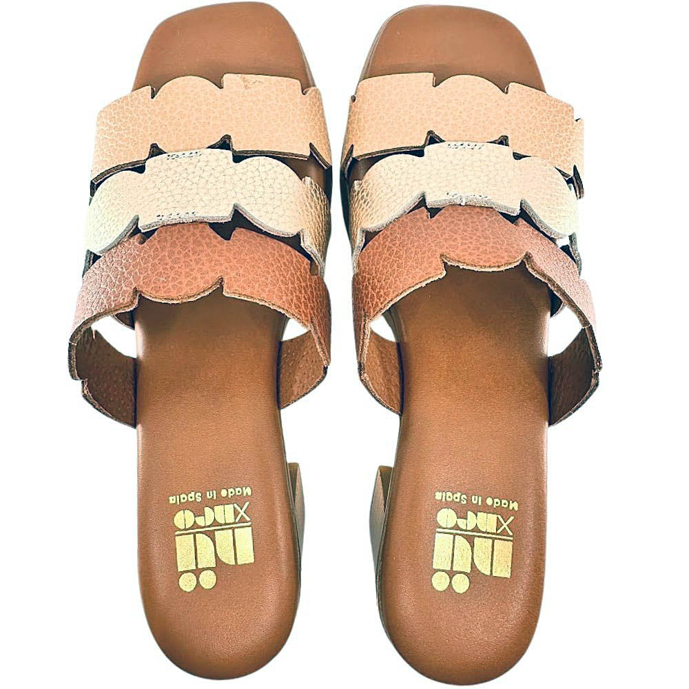 A pair of women's slide sandals with geometric leather straps in beige, gold, and tan, featuring a brown wedge heel and a gold 'Nu X Neo' logo on the footbed.