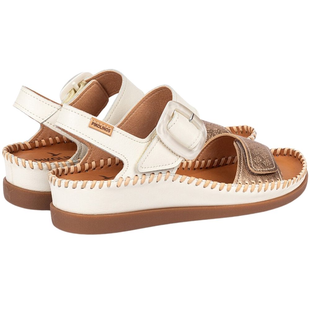 A pair of Pikolinos open-toe flat sandals in off-white leather with a metallic gold strap, brown stitching, and a brown rubber sole, shown against a plain white background.