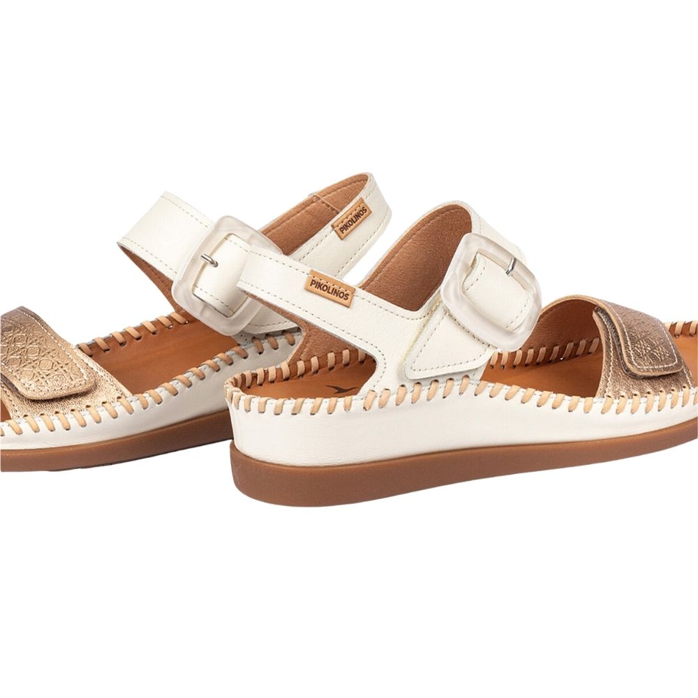 A pair of women's slide sandals in off-white leather with metallic gold textured accents on the toe straps, featuring adjustable buckle straps and a brown sole, shown on a white background.