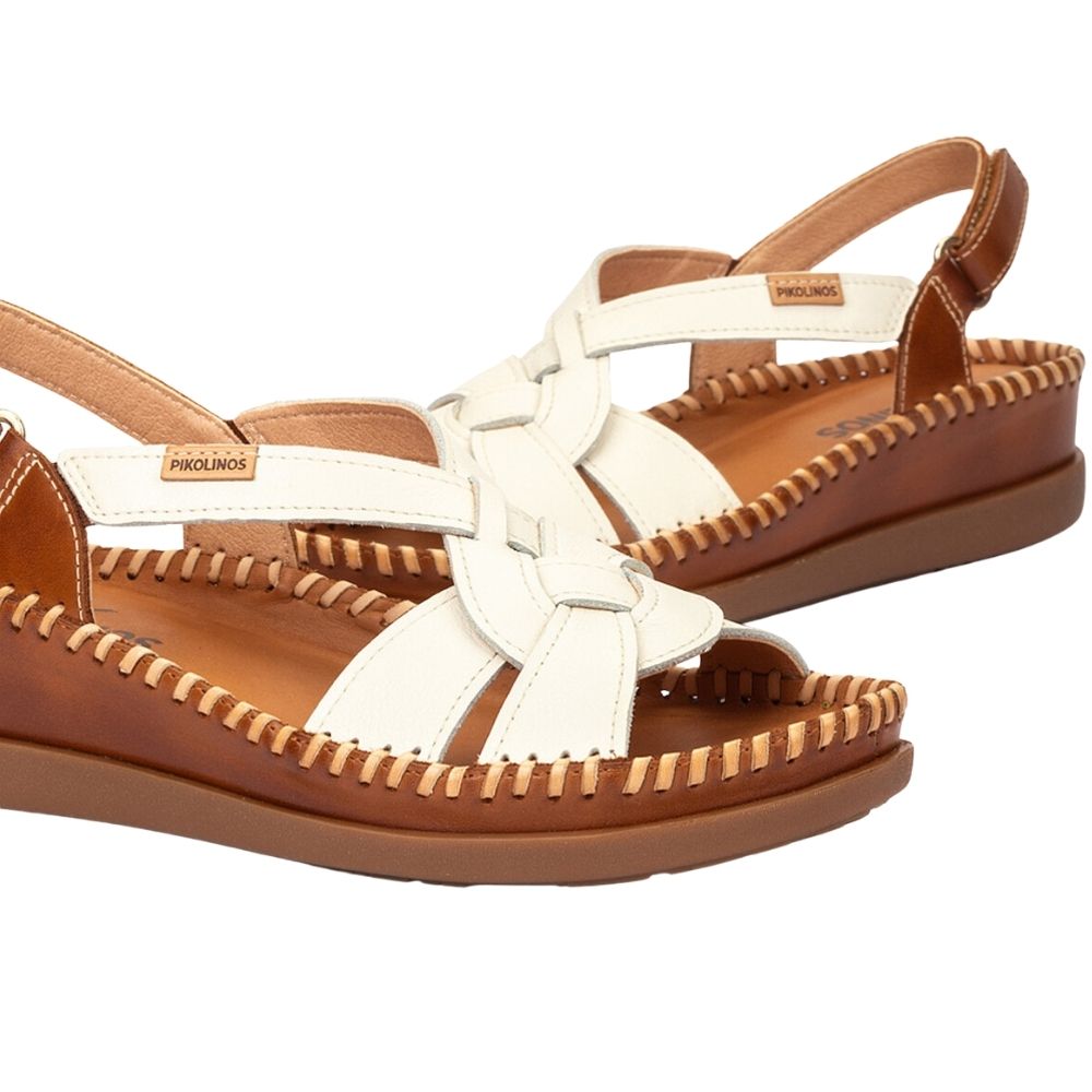 A pair of women's wedge sandals by Pikolinos, featuring off-white woven straps and a brown leather footbed and sole, shown on a plain white background.