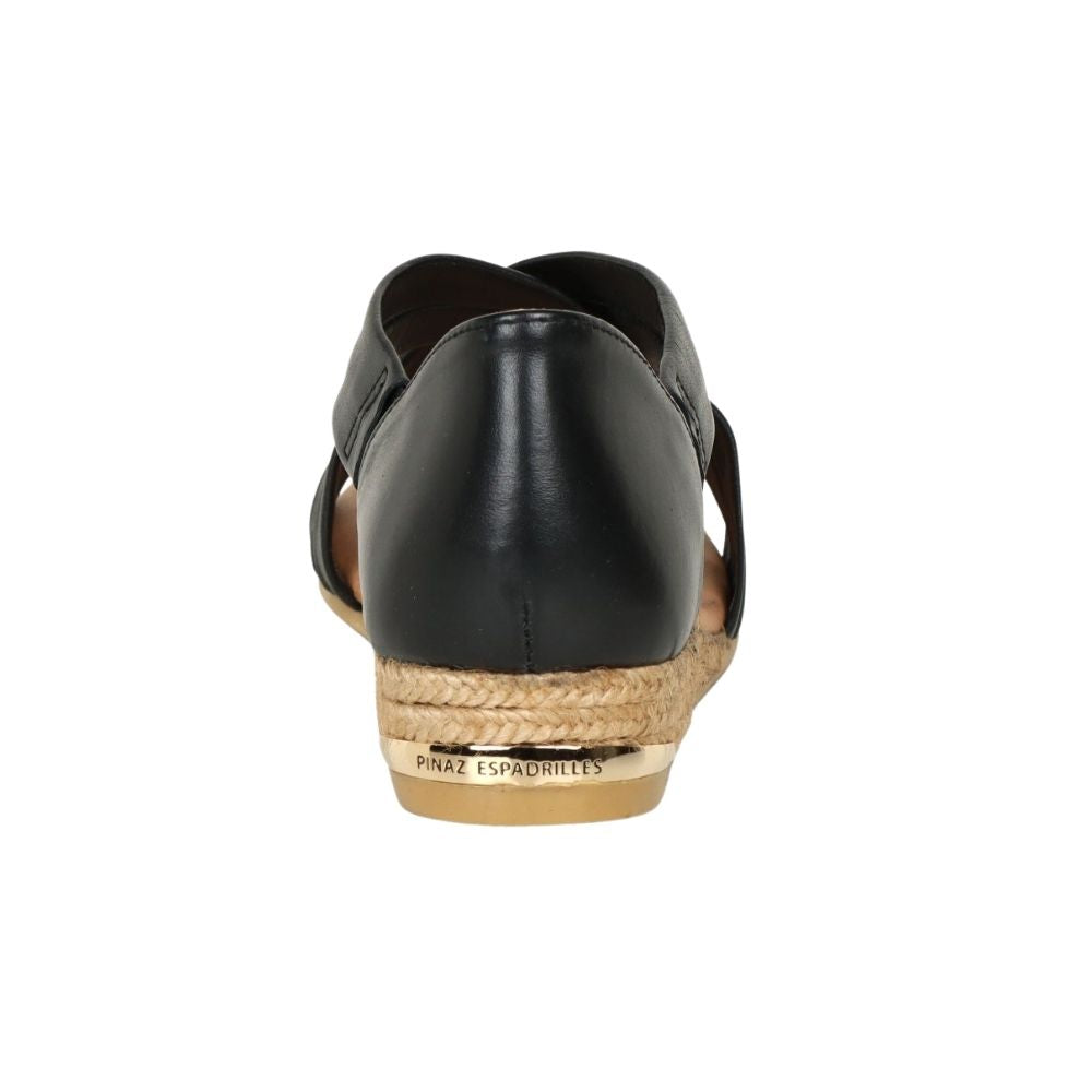 A single black leather espadrille wedge shoe shown from a rear three-quarter view, featuring a braided jute platform and a metallic gold heel accent, on a solid white background.