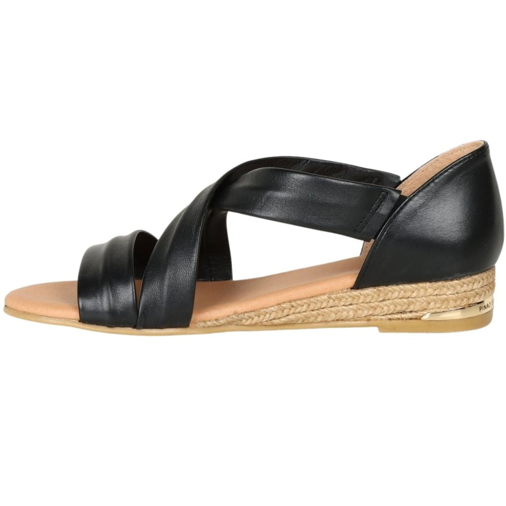 A black leather espadrille wedge sandal with crisscrossing straps, a tan insole, and a braided jute wedge heel, shown in a side profile on a white background.