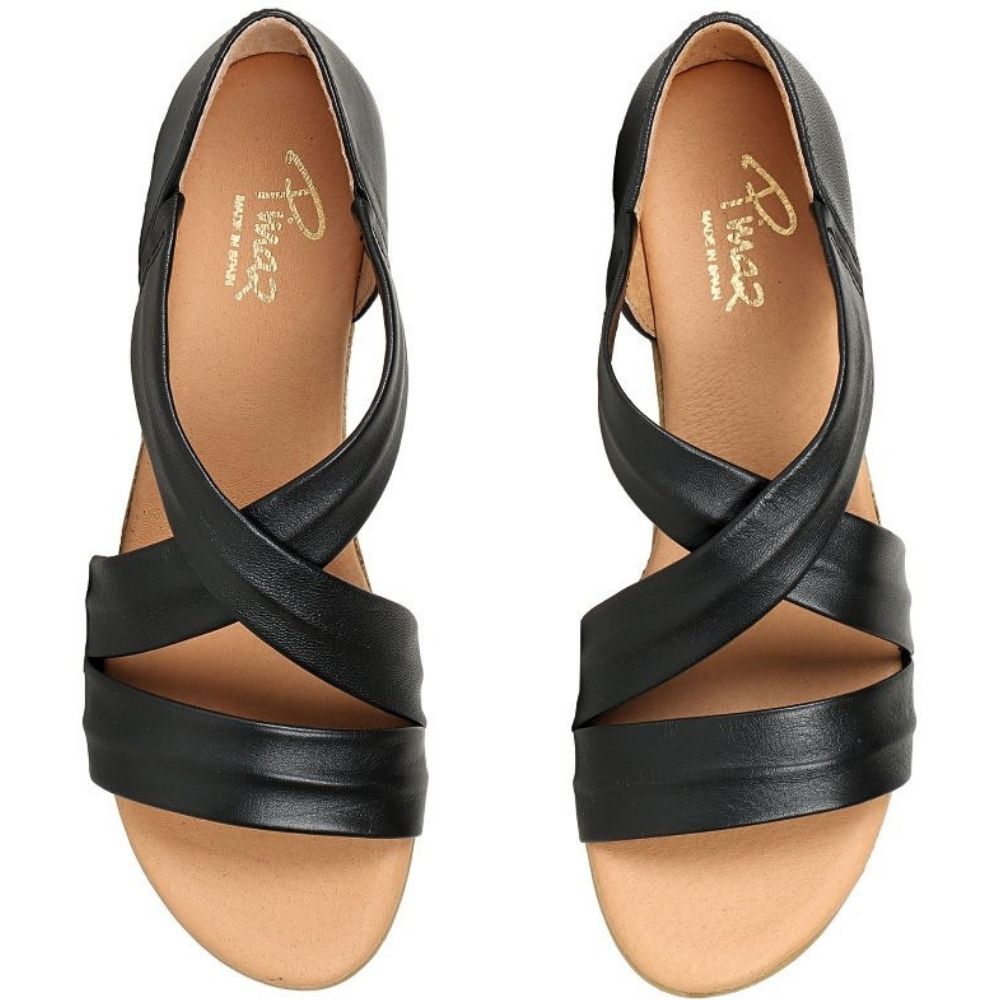 A pair of black leather strappy sandals with a low wedge heel, shown from a top-down view on a white background. The tan insole features the brand name 'Pinaz' printed in gold.