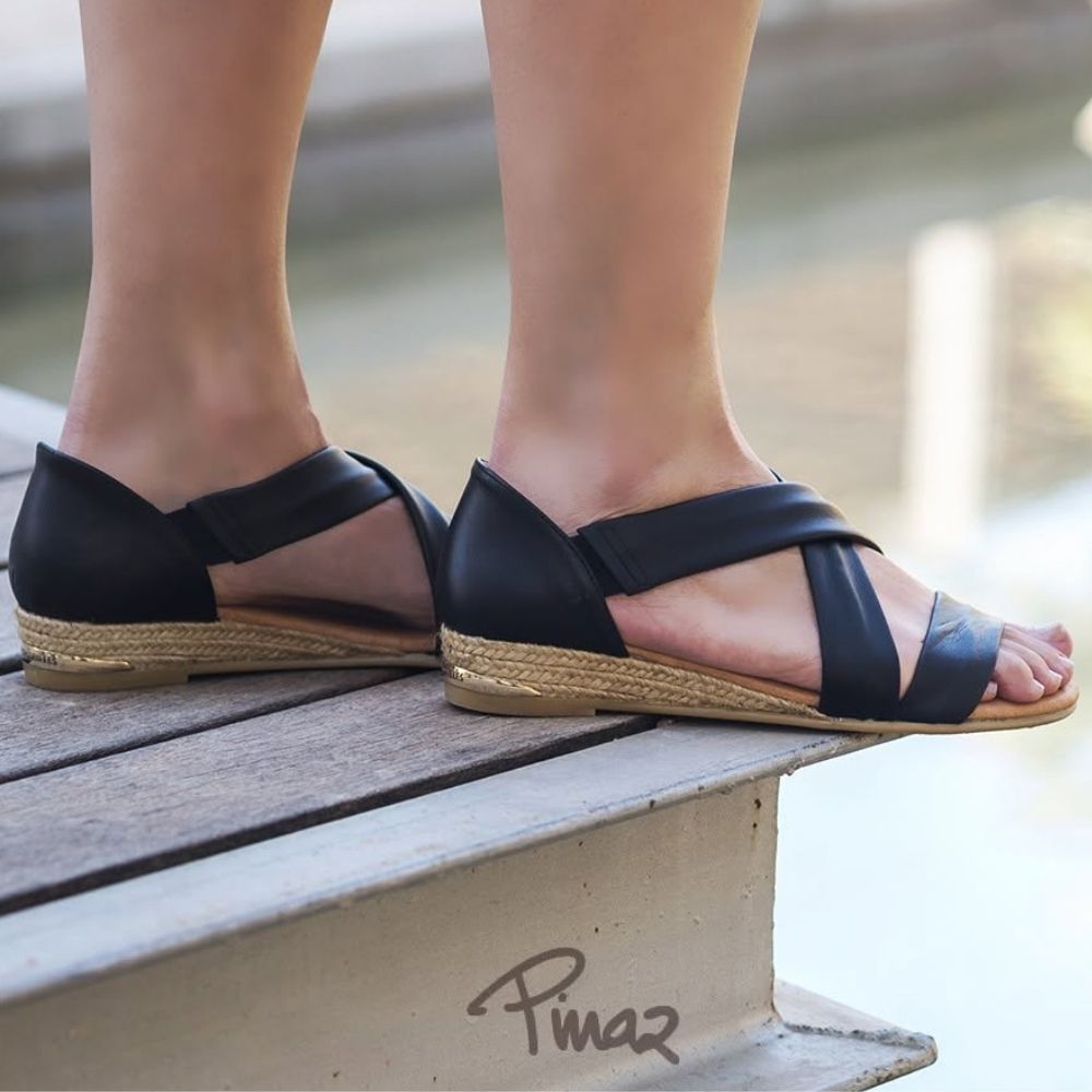 Person wearing black espadrille sandals standing on a deck.