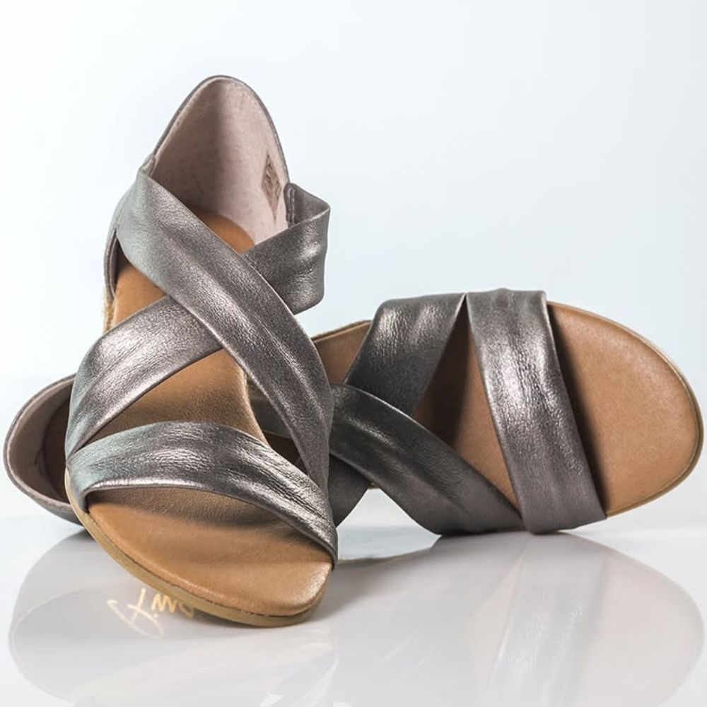 A pair of metallic pewter espadrille sandals with tan footbeds, displayed on a reflective white surface against a light gray background.