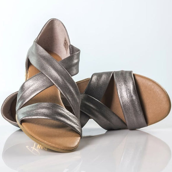 A pair of metallic pewter espadrille sandals with tan footbeds, displayed on a reflective white surface against a light gray background.