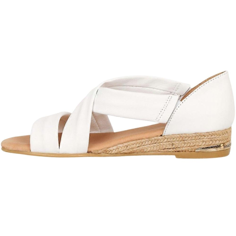 A white leather sandal with crisscrossing straps and a braided jute espadrille heel, shown in a side profile on a white background.