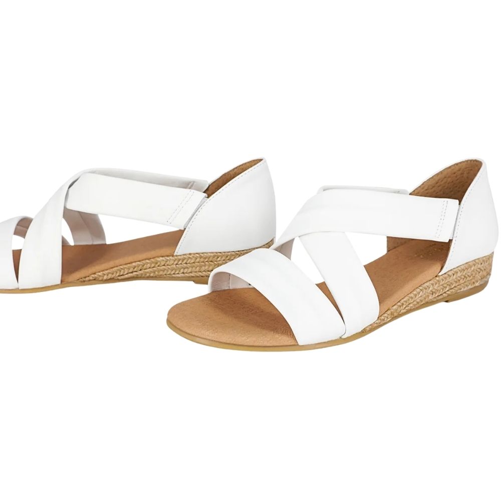 A pair of white leather sandals with a crossover design on braided jute espadrille soles on a white background.
