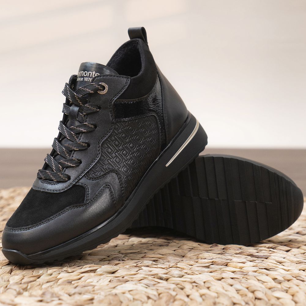 Black sneaker with patterned design on a woven surface