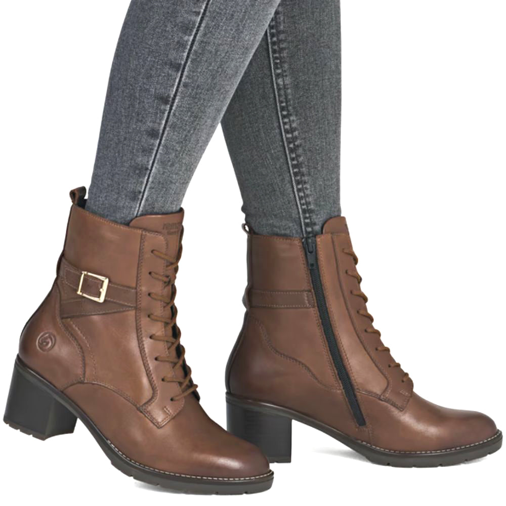 Brown leather boots with a buckle on gray jeans against a white background