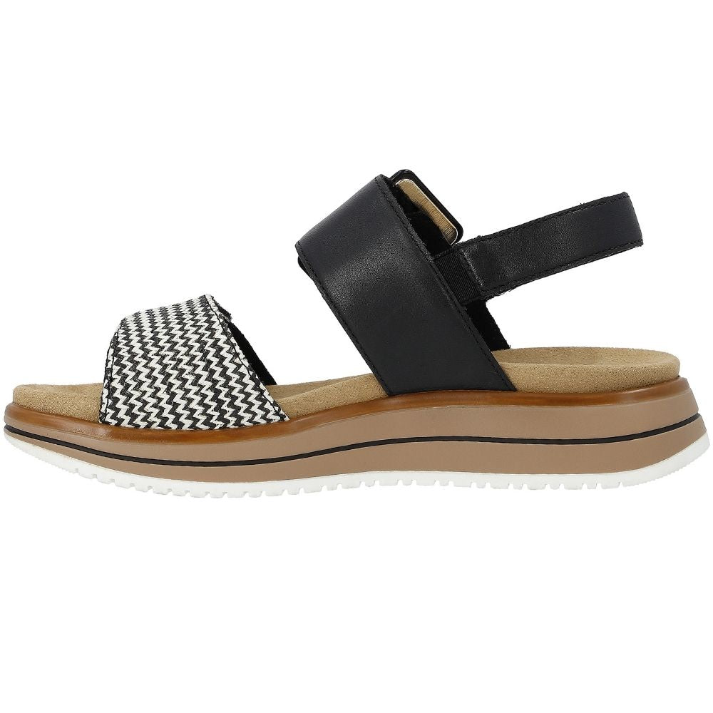 A women's platform sandal featuring a wide black leather strap, a black and white chevron patterned toe strap, and a thick brown midsole on a white outsole.