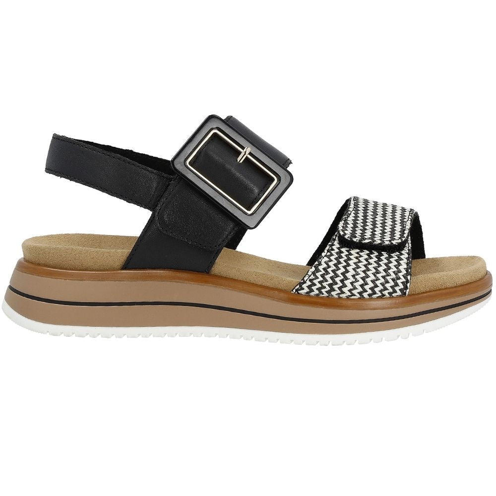 A women's platform sandal featuring a wide black leather ankle strap with a square buckle, a black and white chevron patterned toe strap, a tan midsole, and a white outsole.