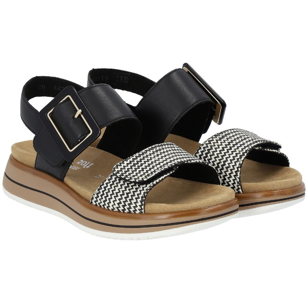 A pair of women's platform sandals featuring black leather straps with gold-tone buckles and a black-and-white chevron patterned front strap, set on a tan footbed with a white and brown sole.