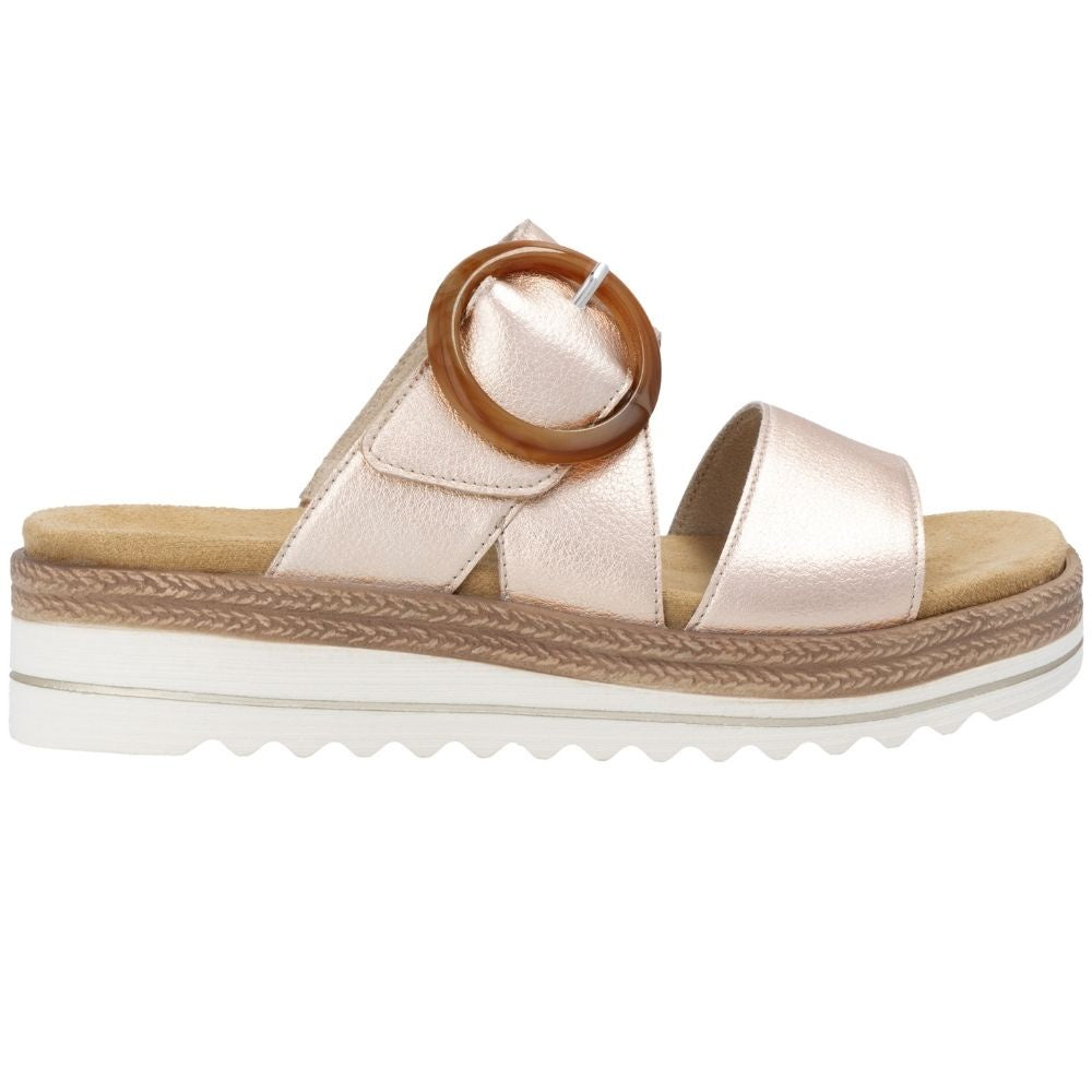 A single women's platform slide sandal in a metallic rose gold leather, featuring a statement buckle on the upper strap and a white platform sole with jute-look detailing.