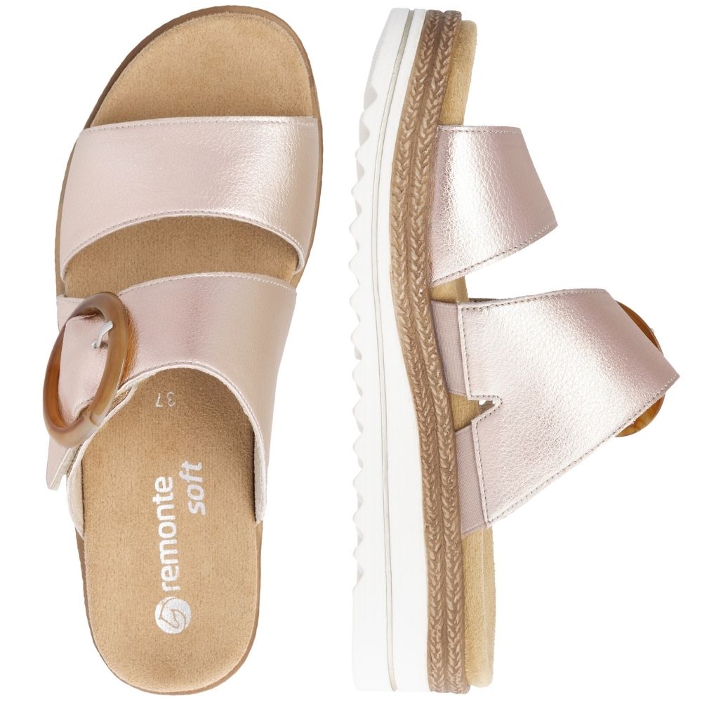 A pair of women's platform slide sandals in a metallic rose gold leather from a top-down view, featuring a statement buckle on the upper strap and a white platform sole with jute-look detailing.