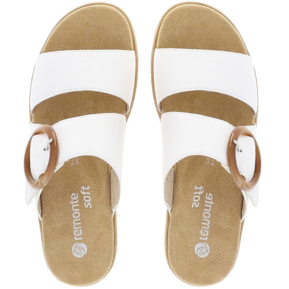 A pair of Remonte Soft slide sandals shown from a top-down view. The sandals feature white straps with an amber statement circular buckle and a tan footbed.