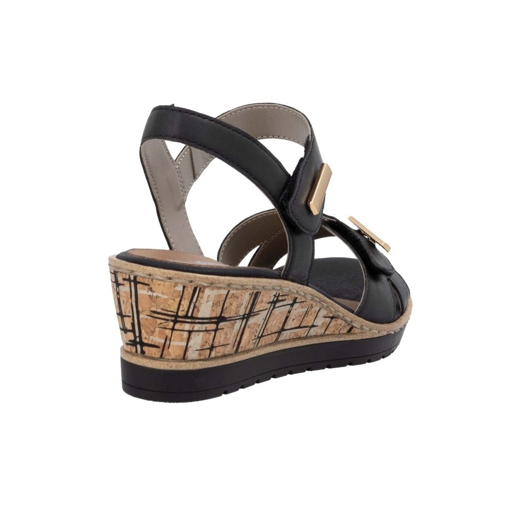 A single women's wedge sandal shown from a side-rear angle on a plain white background. The sandal features black leather straps with a small gold-tone buckle, a tan cork-look wedge heel, and a black outsole.