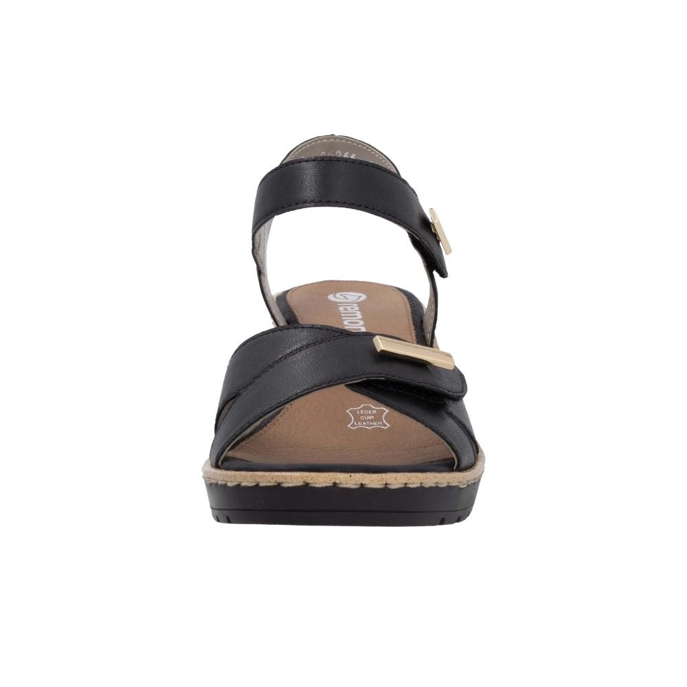 A single black leather wedge sandal with an ankle strap and a wide front strap, featuring gold-tone metal accents and a brown insole, shown from a front-facing perspective on a white background.
