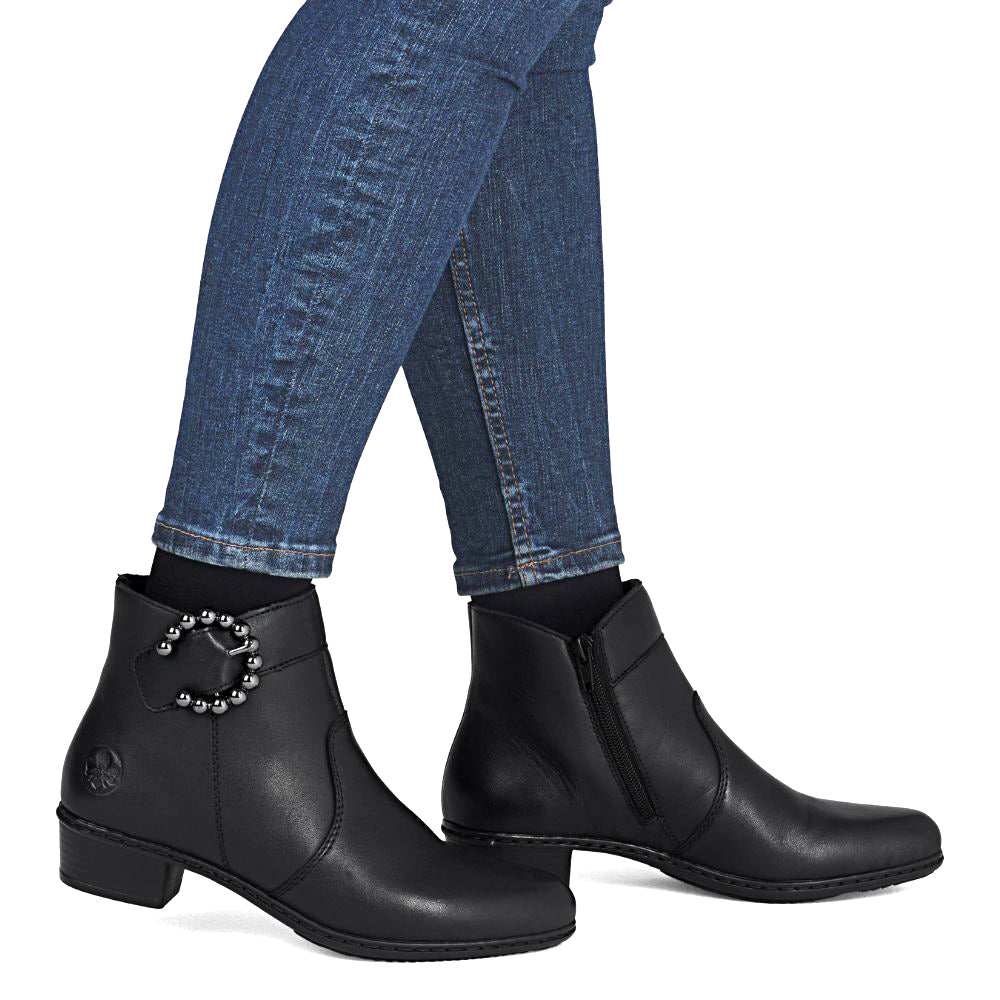 Black ankle boots worn with blue jeans on a white background