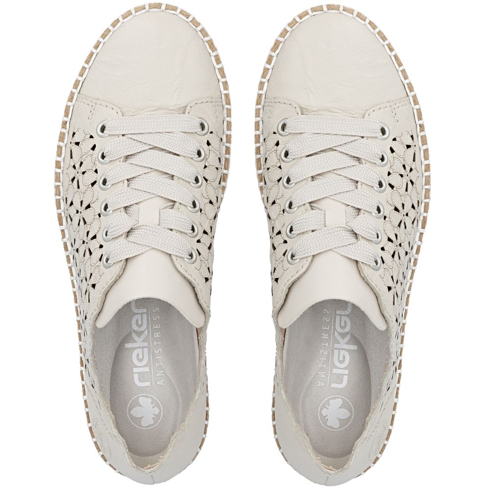 A pair of cream leather slip-on shoes with laser-cut geometric patterns on the sides, matching laces, and a white cleated sole with a jute trim edge, shown from a top-down view on a white background.